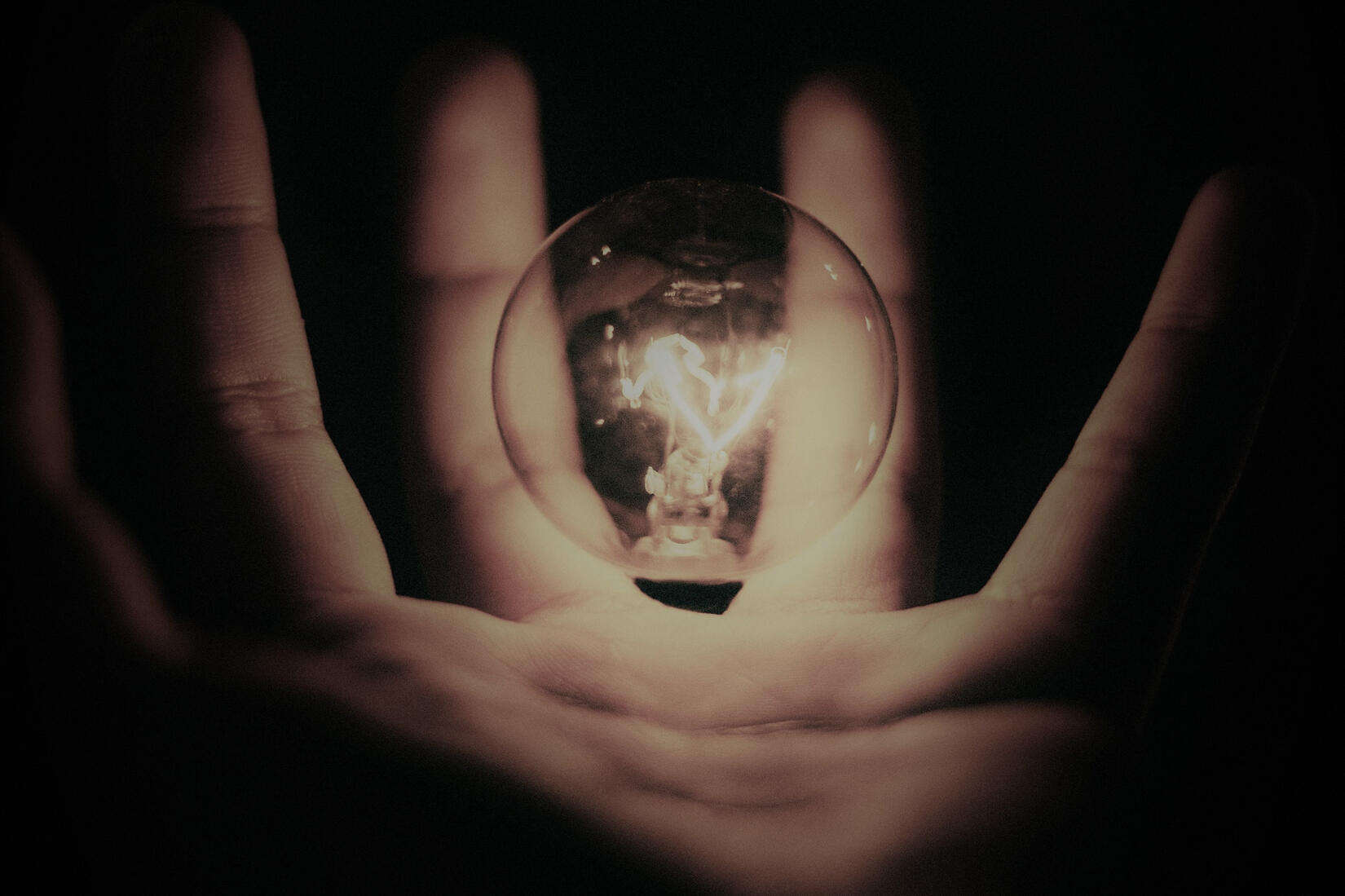 Hand holding a glowing light bulb